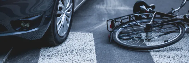 Vélo couché sur un passage piéton à côté d'une voiture après un accident — droits et indemnisation du cycliste victime